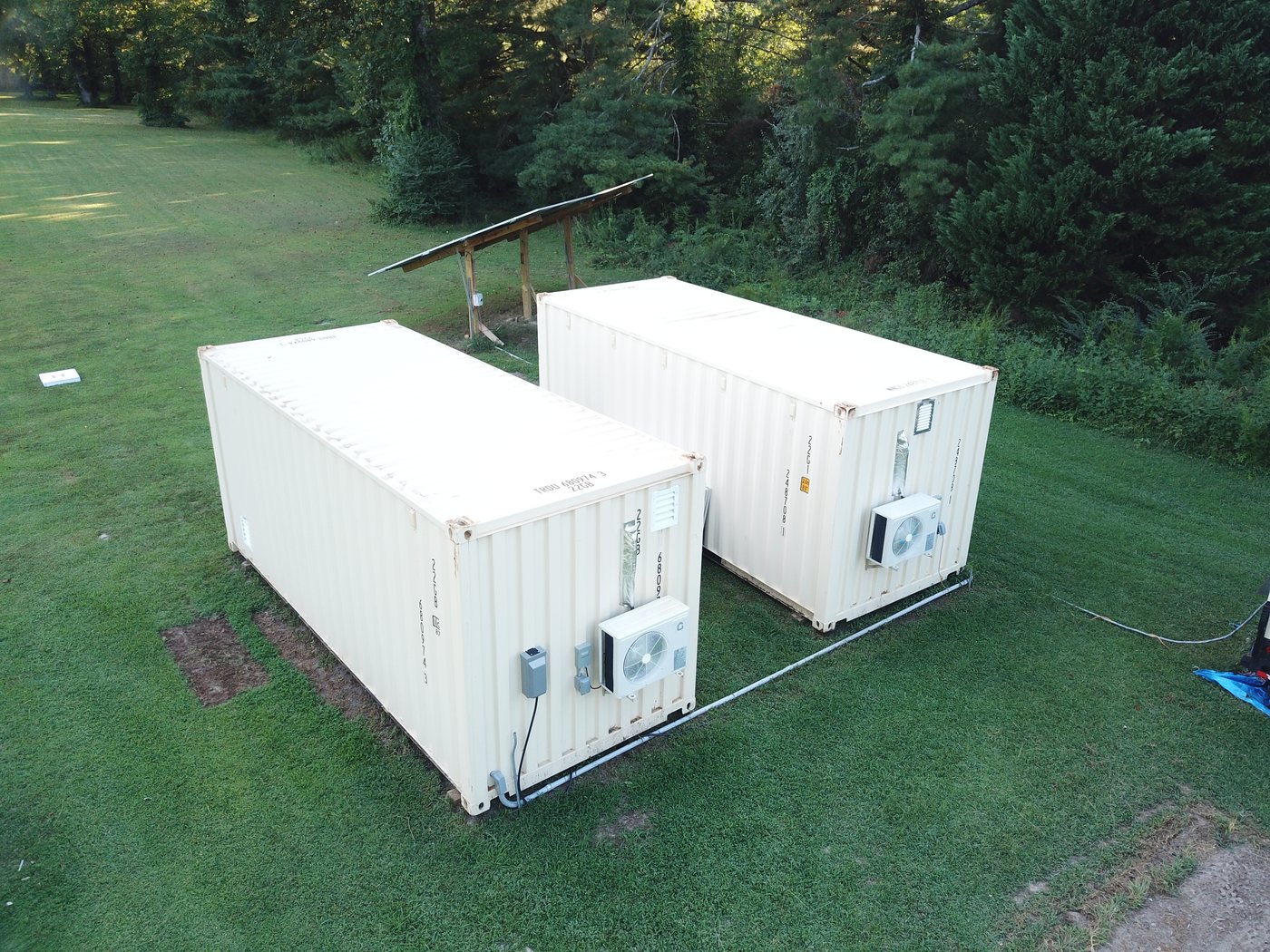 Aerial close view of the two Eclipse containers with mini-split condensers and conduit runs, solar array behind